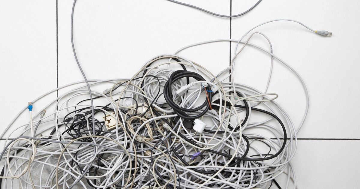 A tangled heap of network and power cables piled on a white tiled floor